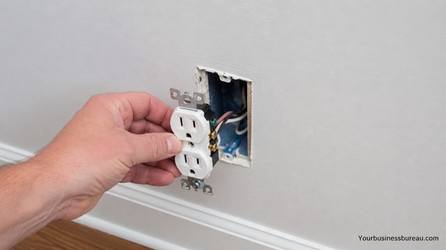 Hand removing an electrical outlet receptacle from wall for inspection